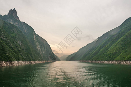 绿水以橙色光照天空进入绿林山和一些悬背景图片