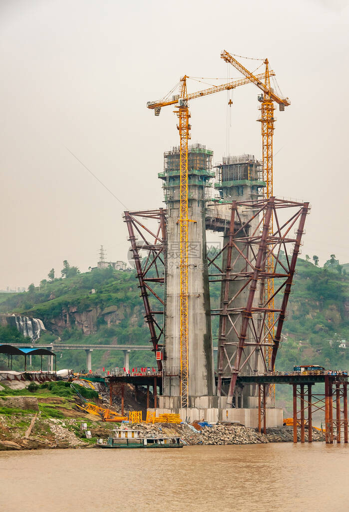 长江正在建设中的桥梁混凝土吊塔特写镜头与2台高大的黄色起重机在棕色的水银色的天空和图片