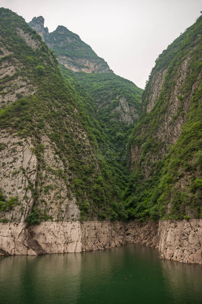 长江巫峡海岸线分裂在绿水背后的银色天空下图片