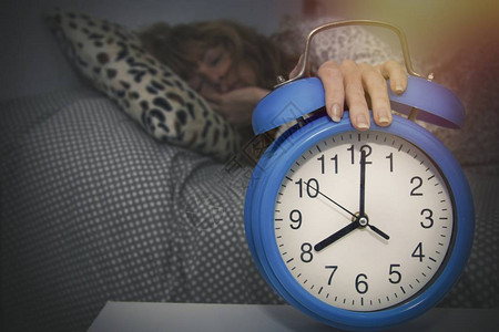 手放在闹钟里睡觉的女人图片