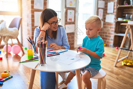 年轻的白种人孩子和老师在幼儿园玩耍母子在游戏室图片