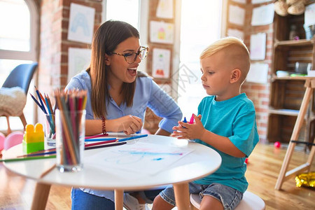 年轻的白种人孩子和老师在幼儿园玩耍母子在游戏室图片