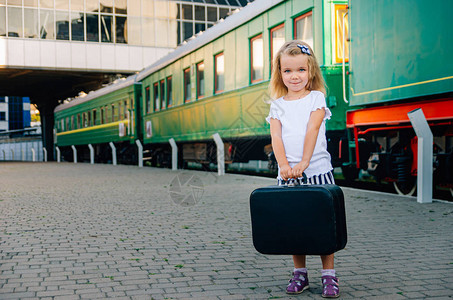 带孩子旅行孩子出海度假一个提着手提箱的女孩站在月台上图片