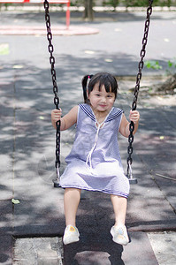女孩或儿童在游乐场的秋千上大笑和摇图片