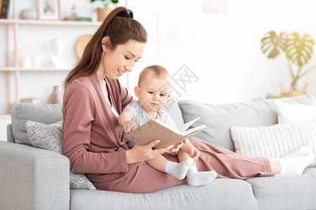 爱护妈阅读书向她可爱的在家的婴儿男孩大声宣读图片