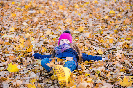 出人意料的小孩躺在金黄色的树叶上秋天可爱的图片