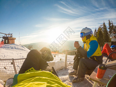 在雪山顶休息的情侣喝热茶滑雪和滑雪图片