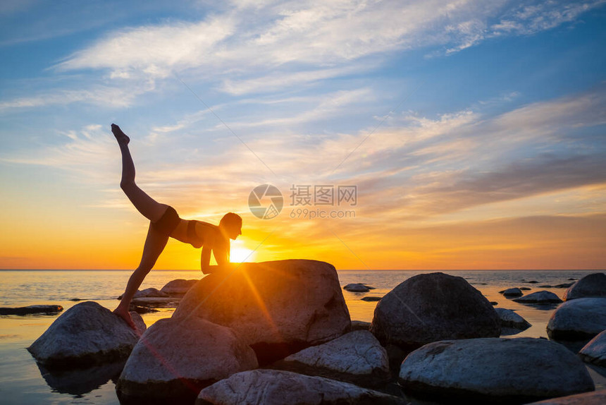 在海边的瑜伽课上裸阳下天对着巨石摆出姿势与鲜艳的图片