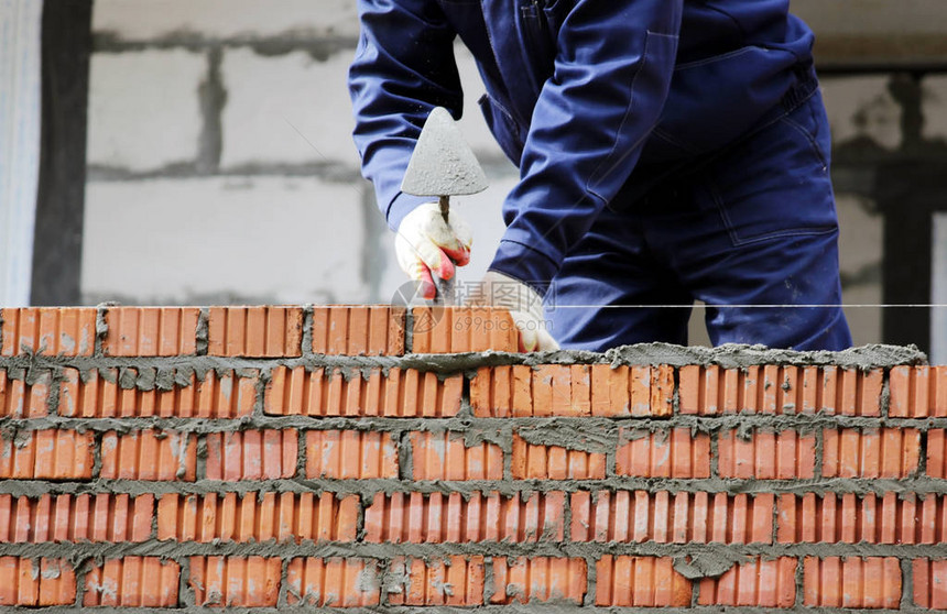 专业建筑工人在工业场地铺砖和建房单图片