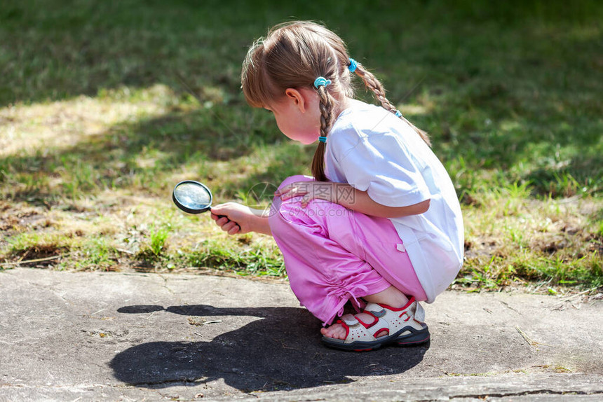好奇的小女孩在后院用放大镜寻找东西图片