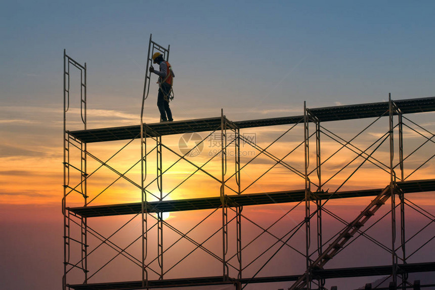 在建筑工地作的人用脚手架和日落背景的建筑图片
