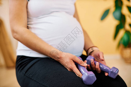 近距离关紧怀孕的中年孕妇她们拿着哑铃图片