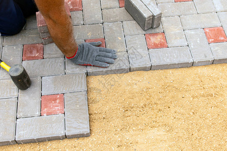 戴手套用橡胶锤子在水泥块上铺设混凝土石图片