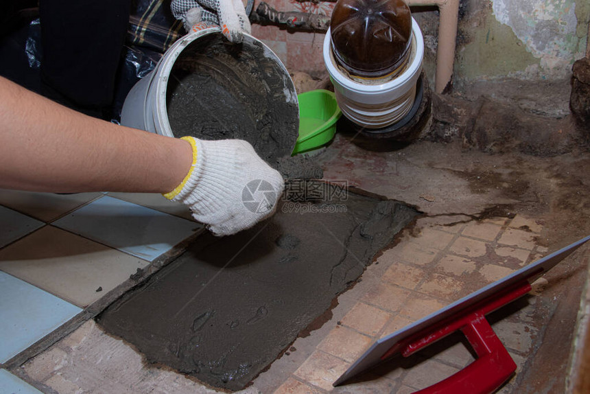 在地板上铺设水泥填满地板男人的工作师父之手液态水泥一个男人用手把水泥抹平图片
