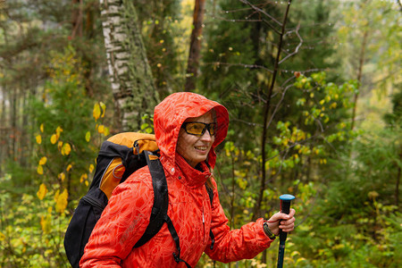 带着背包的微笑女旅行者在雨季穿过秋雨林图片