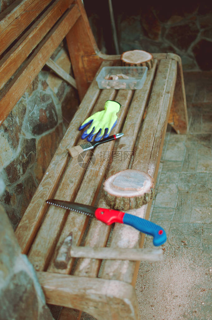 一把旧锤子一只手锯防护手套和一张长凳上带锯尘的圆松木束Wooden代表主菜类的食物图片