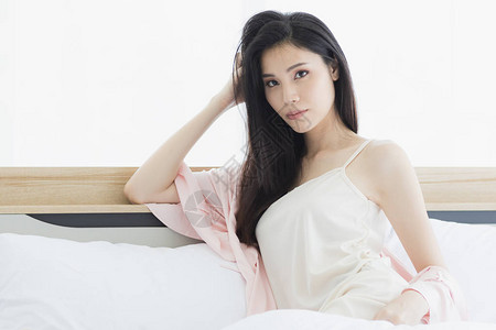 美丽的亚洲女模特儿坐在床上穿着卧室的感睡衣图片