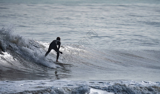 孤立的男子冲浪者在波浪上的后视轮廓图片