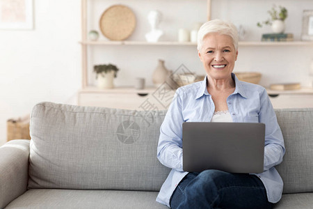 美丽的老年妇女在家用笔记本电脑工作图片