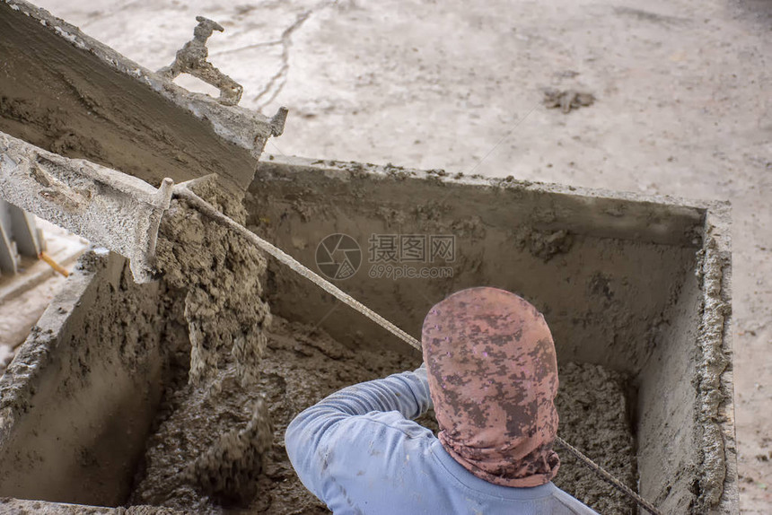 工人把最后一批湿水泥混凝土从Clue卡车槽倒入金属桶图片