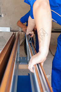 建设理念下的改善建筑两名专业工人在新房车库门系统上安装金属导轨的垂图片