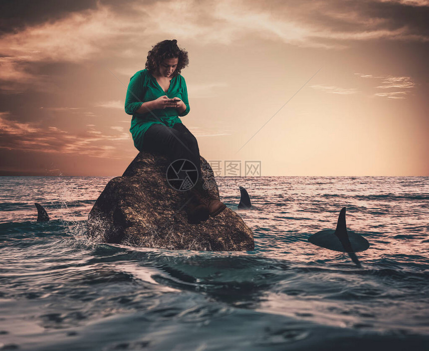 在海中被鲨鱼包围的岩石上年轻女无图片
