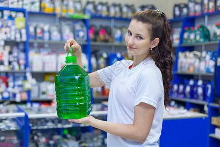 年轻女销售员在汽车零件商店为洗车挡风玻璃提供一瓶不冻清洁液在图片