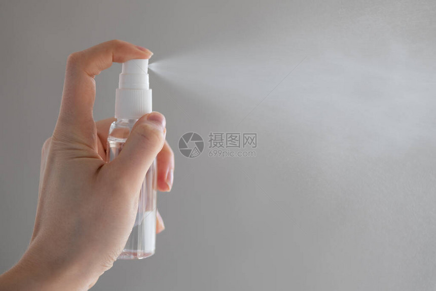 女或女孩在手部使用喷雾消毒酒精产品消毒手部以防止灰色背景下的图片