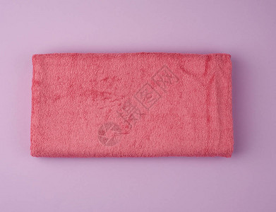 紫色背景上的折叠浴巾粉红色毛巾顶视图图片