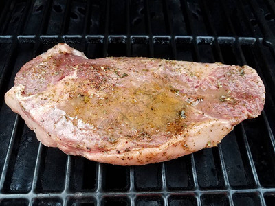烧烤架上的生牛排肉配液体或腌料图片