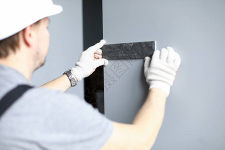 戴手套和头盔的建筑工人为公寓的墙壁挑选瓷砖的颜色男人将建筑材料图片