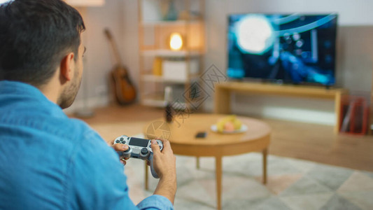 坐在沙发上的男人拿着控制器玩控制台视频游戏图片