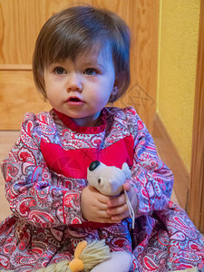 迷人的两岁婴儿在她家的走廊里玩着一只毛绒玩具图片