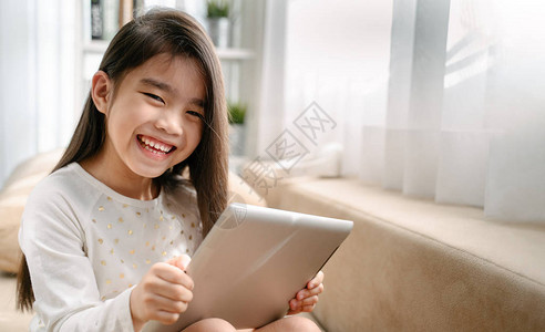 亚洲小女孩玩智能手机技术和通信概念图片