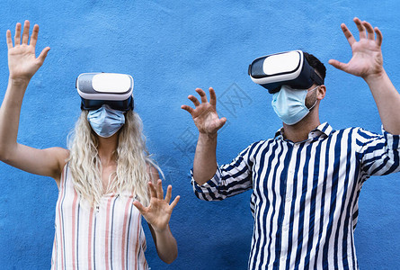 爆发期间戴口罩的年轻夫妇玩虚拟现实眼镜图片