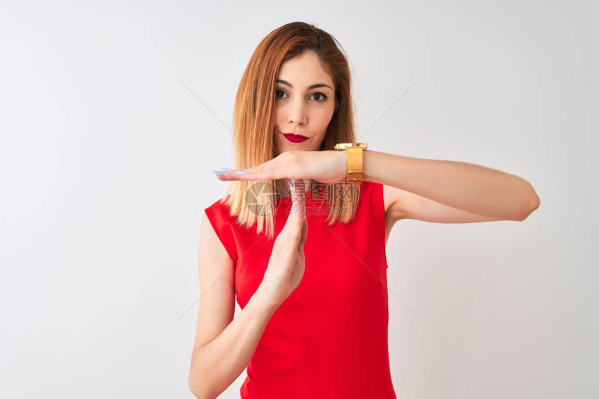 身穿优雅红色连衣裙的红发女商人站在孤立的白色背景上用手沮丧和严肃的图片