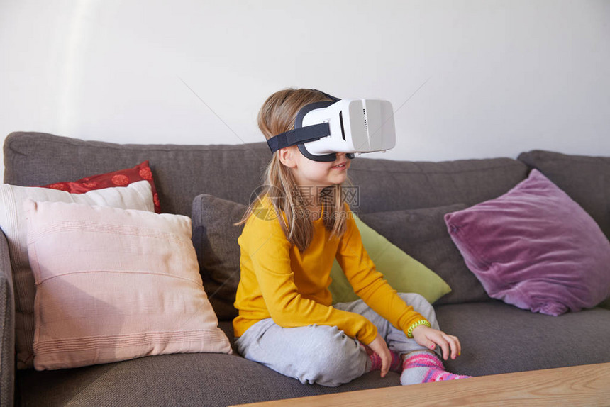 六岁小孩坐在棕色沙发上在家看虚拟现实耳图片