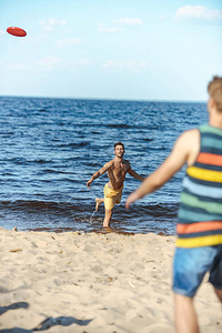在沙滩上玩飞盘的年轻男子有图片