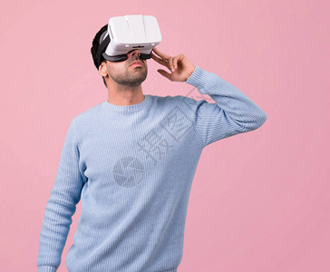 使用VR眼镜穿蓝色毛衣的男人关于粉红色背景的图片