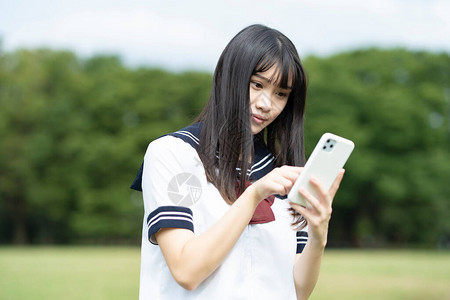 触摸智能手机屏幕的亚洲女中学生Asia图片