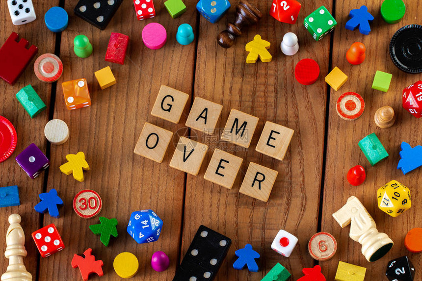 游戏结束用木制字母瓷砖拼出被骰子纸牌和其他木制背景上的图片