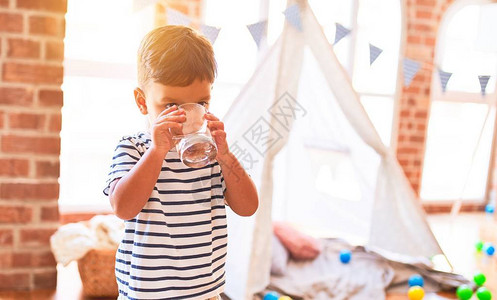 美丽的小孩男在幼儿园喝杯水图片