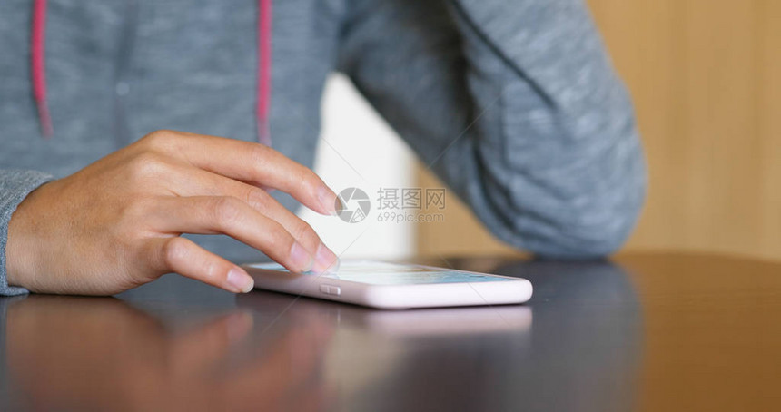女人触摸放在桌子上的手机图片