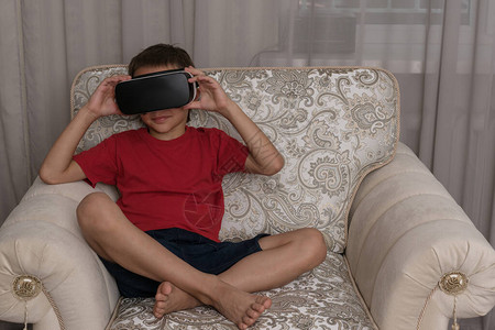 特写男孩在虚拟现实眼镜坐在大扶手椅上的图像图片
