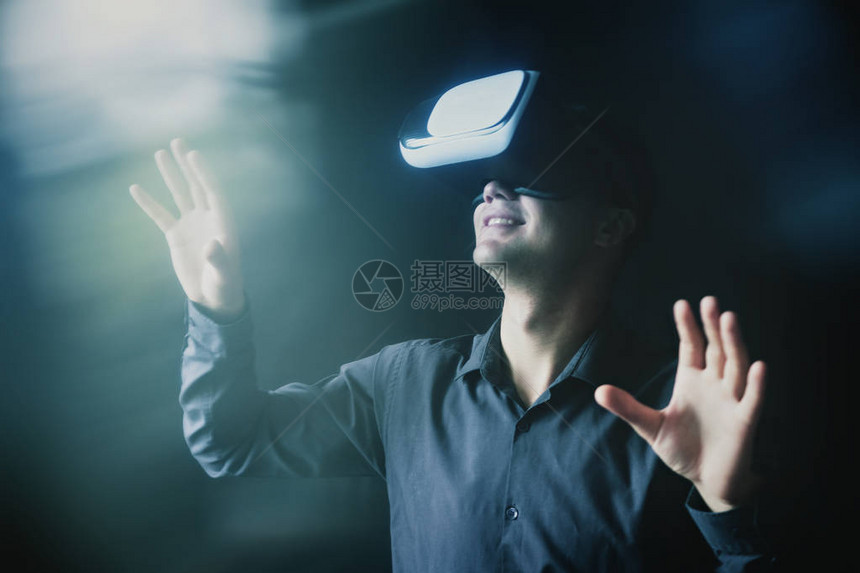 身戴VR头盔的男人与模拟虚现实环境以光耀斑互动的合成图像图片