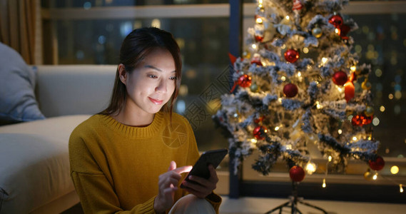 妇女在家里使用带有圣诞节树装饰品图片