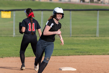 高中女垒球运动员在二垒周围全速跑来去面高清图片