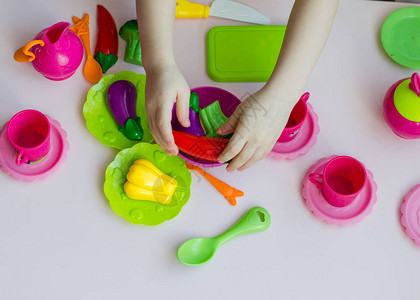 小女孩用塑料盘子和蔬菜玩具厨师图片