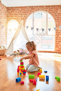 美丽的金发小金发美女孩玩塑料砖在幼儿园图片