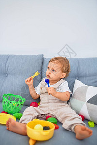 坐在沙发上坐着在家玩塑料餐玩具的金图片
